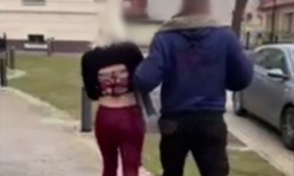 Zatrzymana kobieta prowadzona przez policjanta