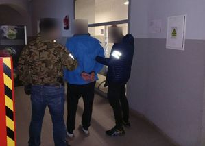 dwaj policjanci prowadzą zatrzymanego - widok z tyłu