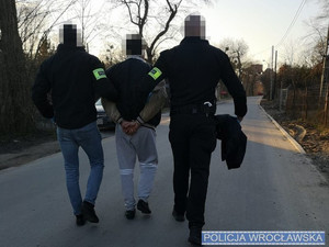 dwaj policjanci prowadza zatrzymanego