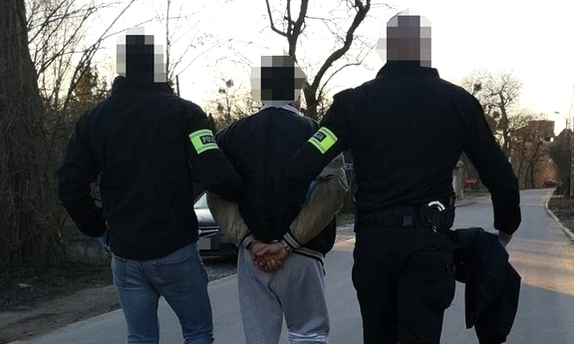 dwaj policjanci prowadza zatrzymanego