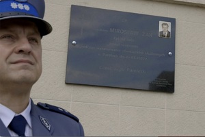 tablica pamiątkowa na część Mirosława Żaka, obok policjant w mundurze wyjściowym