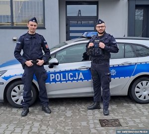 dwaj policjanci stoją przy radiowozie