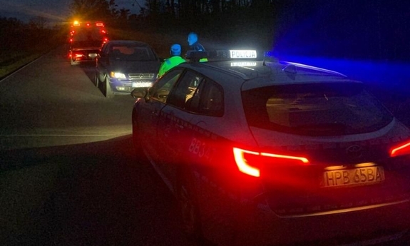 Na zdjęciu radiowóz, policjanci i samochód zatrzymanego mężczyzny oraz laweta