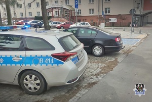 na zdjęciu radiowóz i eskortowany samochód stojący na parkingu przed szpitalem