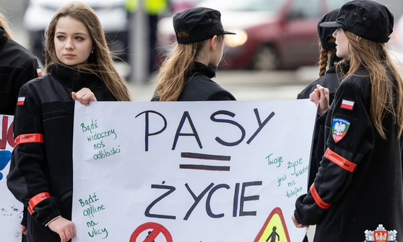 dwie uczennice klasy o profilu policyjnym trzymają plakat z napisem pasy = zycie