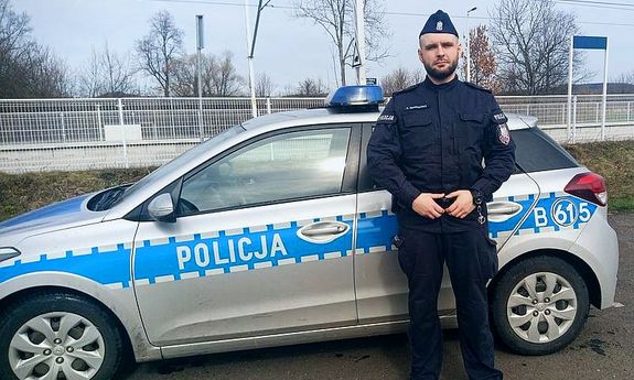 umundurowany policjant stoi przy radiowozie