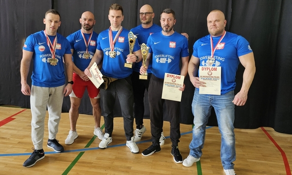 sześciu zawodników pozuje do zdjęcia, na szyjach mają zawieszone medale, w dłoniach trzymają dyplomy