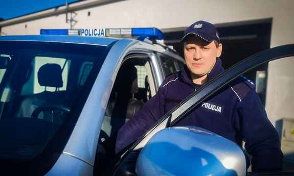 policjant stojący przy radiowozie