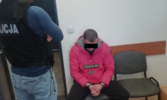 policjant z zatrzymanym zakutym w kajdanki