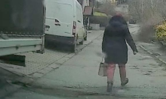 idąca ulicą kobieta, po lewej stronie stoją zaparkowane samochody