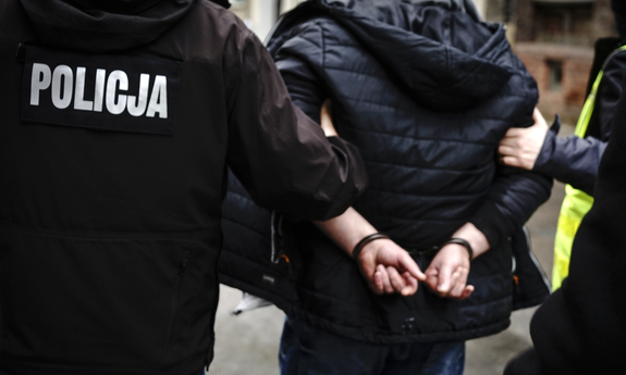 policjanci prowadzą zatrzymanego skutego w kajdanki
