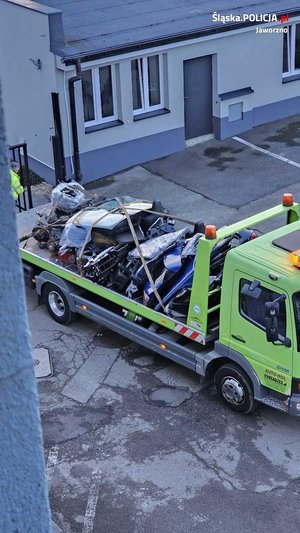 na zdjęciu laweta, która ma na pace załadowane i zabezpieczone części samochodowe