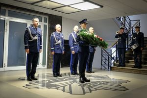 Komendant Główny Policji wraz z trzema zastępcami oddają hołd poległym przed Tablicą Pamięci, przed nimi policjant z wieńcem, a z boku widoczni są dobosz i dwaj trębacze