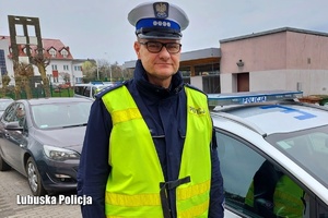 policjant ruchu drogowego w żółtej kamizelce stoi przed radiowozem