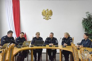 umundurowani funkcjonariusze Policji siedzący za stołem ustawionym w podkowę