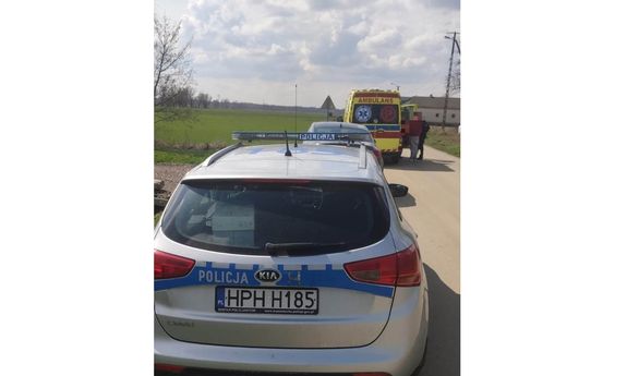 policyjny radiowóz a przed nim ambulans pogotowia i stojące przy nim osoby