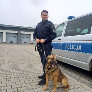 policjant z psem służbowym stoją przy radiowozie