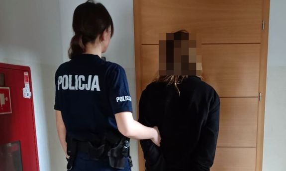 Zdjęcie przedstawia umundurowaną policjantkę, która prowadzi po swojej prawej stronie zatrzymaną kobietę.