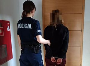 Zdjęcie przedstawia umundurowaną policjantkę, która prowadzi po swojej prawej stronie zatrzymaną kobietę.