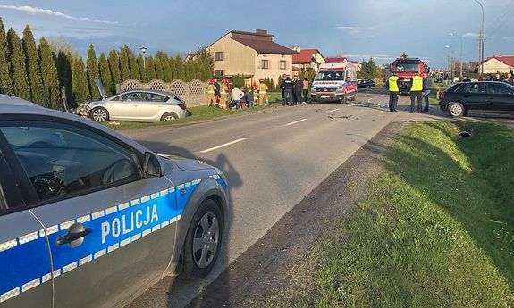 Zdjęcie przedstawia fragment oznakowanego radiowozu stojącego przy drodze.