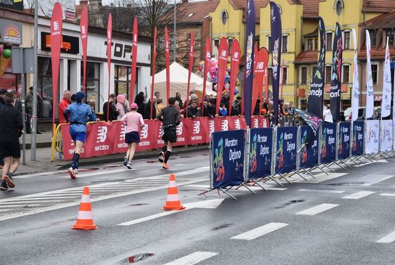 uczestnicy maratonu podczas biegu - widok na zawodników z tyłu. Z boku widać oglądające maraton i kibicujące zawodnikom osoby