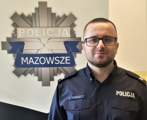 umundurowany policjant na tle logo z gwiazdą policyjną