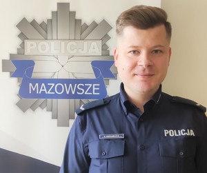 umundurowany policjant na tle logo z gwiazdą policyjną