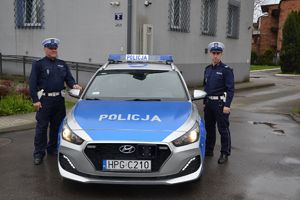 policjanci ruchu drogowego stojący przy radiowozie