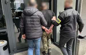 Dwóch policjantów prowadzi zatrzymanego mężczyznę