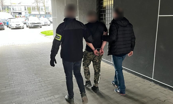 Dwóch policjantów prowadzi zatrzymanego mężczyznę