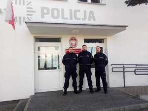 trzech umundurowanych policjantów stoi przy drzwiach wejściowcyh do posterunku policji