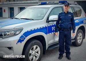 umundurowany policjant stoi przy radiowozie