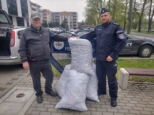 przekazanie nakrętek w tle budynek komendy i pojazdy