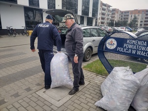 przekazanie nakrętek w tle budynek komendy i pojazdy