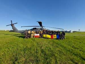 Zdjęcie grupowe na tle policyjnego śmigłowca Black Hawk, pozujący trzymają flagi.