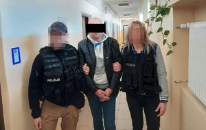 policjanci na korytarzu z zatrzymanym mężczyzną