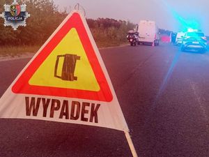 Na zdjęciu znak z napisem wypadek w dali policja, pogotowie pracujące przy wypadku drogowym