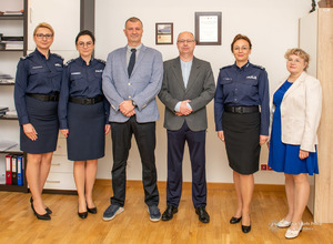 uczestnicy spotkania pozują do zdjęcia. Od lewej stoją dwie policjantki, obok dwaj mężczyźni w garniturach, policjantka i kobieta ubrana po cywilnemu