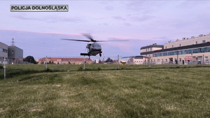 Policyjny śmigłowiec Black Hawk podchodzi do lądowania na trawiastym lądowisku.