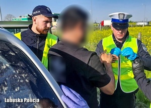 Policjanci stoją obok zatrzymanego mężczyzny