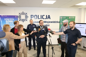 Główny Inspektor Ochrony Środowiska udziela wywiadu dziennikarzom, za nim stoi zastępca Komendanta Głównego Policji