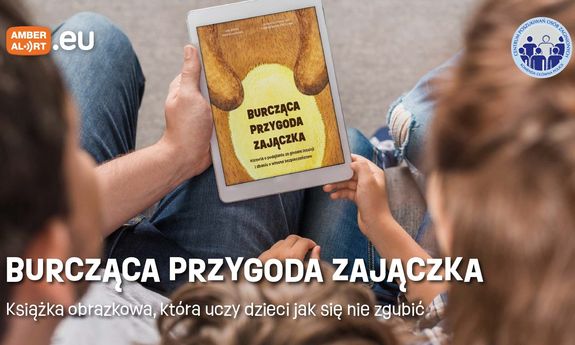 obrazek na którym rodzic trzyma z dzieckiem książeczkę: Burcząca przygoda zajączka. Powyżej po lewej stronie znajduje się logo amber alert, a po prawej logo Centrum Poszukiwań Osób Zaginionych KGP. Poniżej na środku widoczny jest biały napis: Burcząca Przygoda Zajączka. Książka obrazkowa, która uczy dzieci jak się nie zgubić.