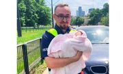 umundurowany policjant trzyma na rękach niemowlę w kocyku