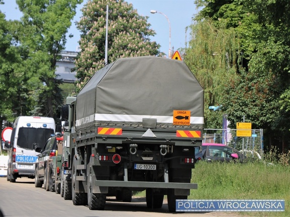 samochody wojskowe i policyjny radiowóz zaparkowane przy ulicy