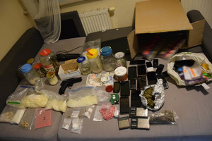 zabezpieczone narkotyki, telefony, nielegalne papierosy, wagi elektroniczne oraz inne rzeczy zabezpieczone przez policjanów znajdujące się na wersalce