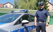 policjant stoi przy radiowozie policyjnym