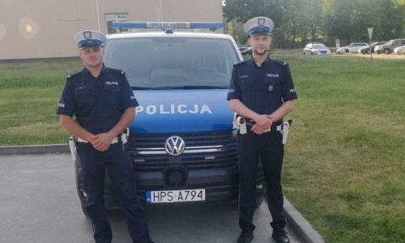 umundurowani policjanci stoją przy radiowozie