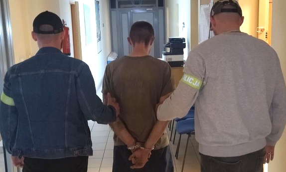 dwaj nieumundurowani policjanci prowadzą zatrzymanego zakutego w kajdanki