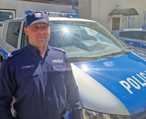 umundurowany policjant stoi przy radiowozie