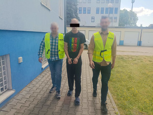 dwóch policjantów prowadzi zatrzymanego mężczyznę